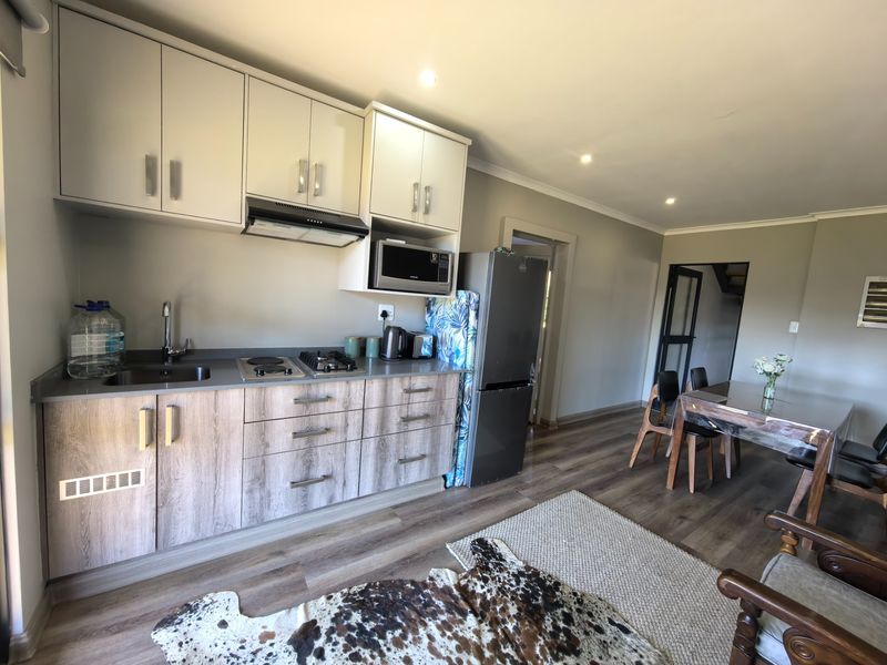 Open-plan kitchen and dining area featuring modern cabinetry, laminate flooring, and integrated appliances, creating a functional and cohesive living space.
