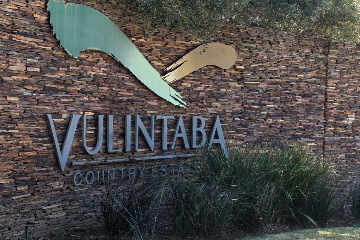 Entrance signage wall for Vulintaba Country Estate featuring natural stone cladding and metal lettering.