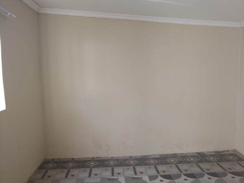 An empty bedroom featuring patterned floor tiles and neutral wall paint, providing a blank canvas for potential interior design updates.