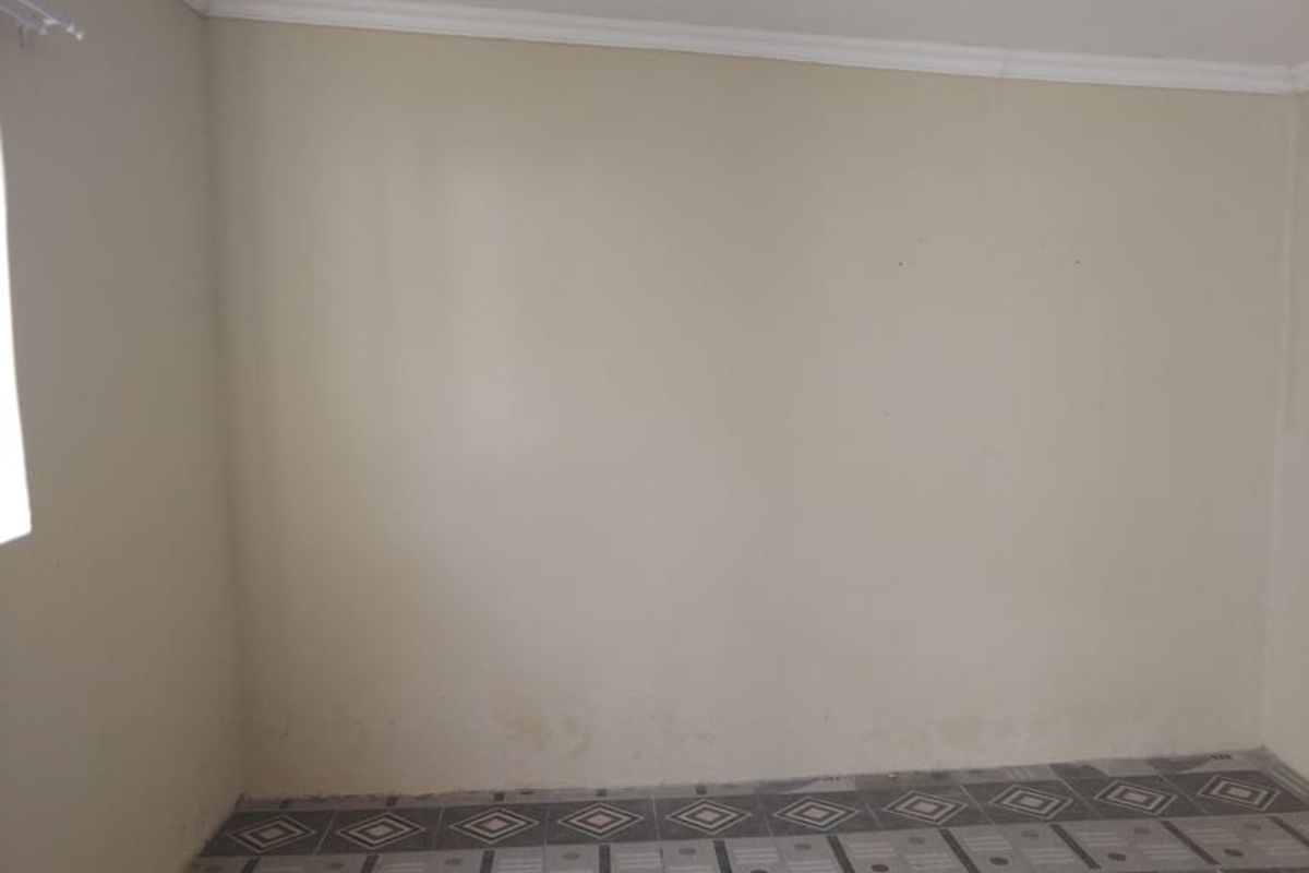 An empty bedroom featuring patterned floor tiles and neutral wall paint, providing a blank canvas for potential interior design updates.