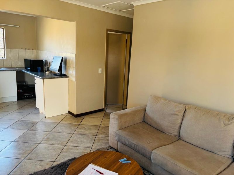 Open-plan living area featuring tiled flooring and a functional kitchen space with cabinetry and tiled backsplash.