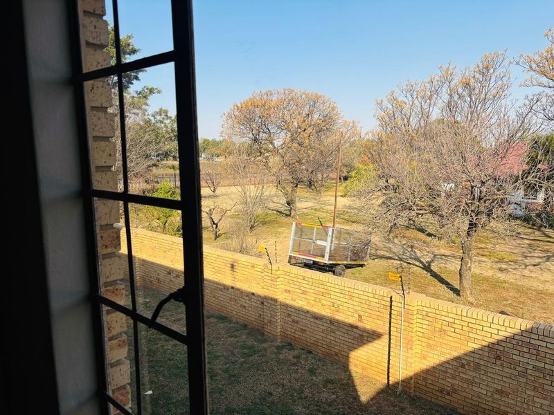 A view from an interior window overlooking a garden area enclosed by a brick boundary wall with electric fencing.