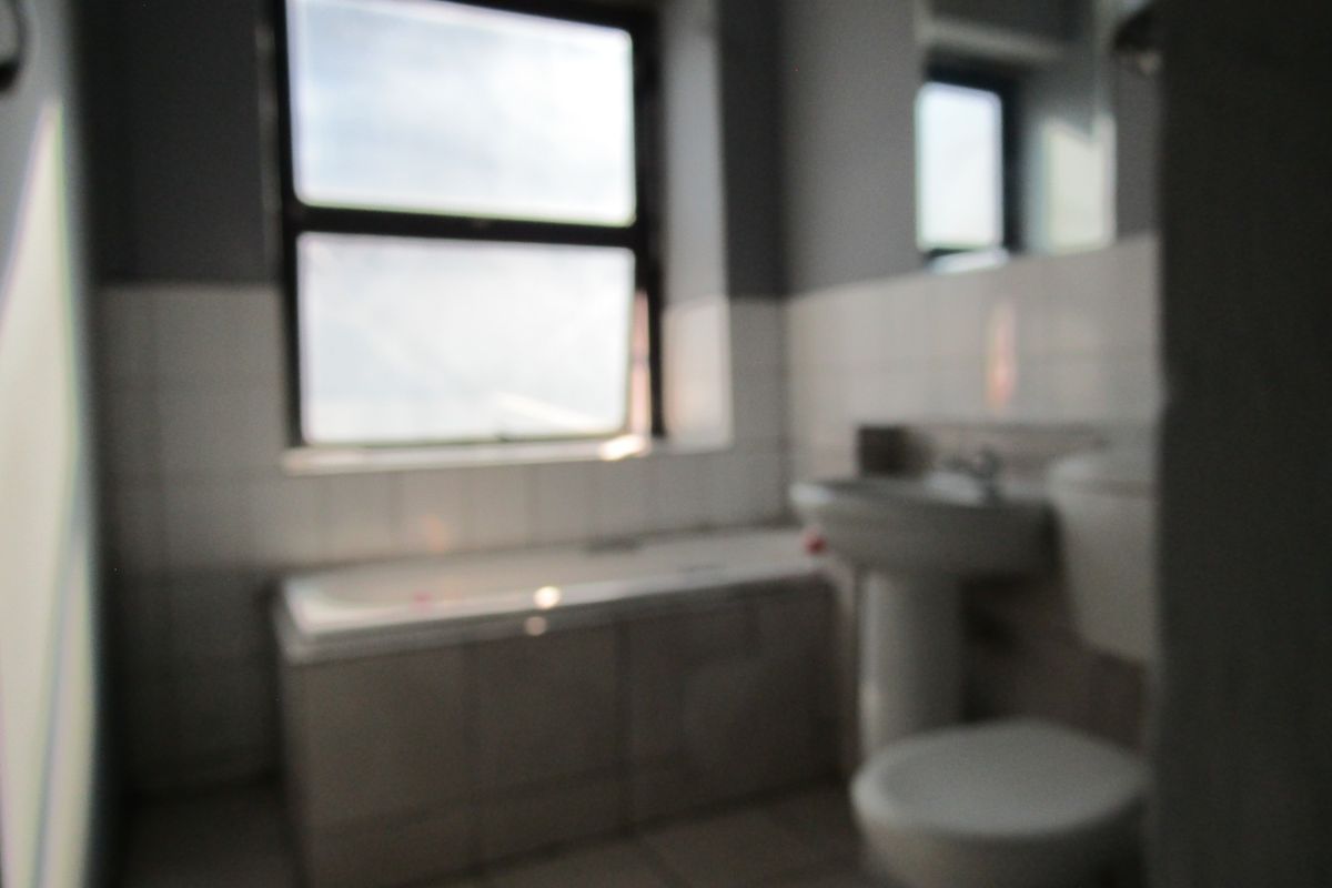 A functional bathroom featuring a bathtub, pedestal basin, and toilet with tiled finishes, requiring a clear, high-quality image for accurate assessment.