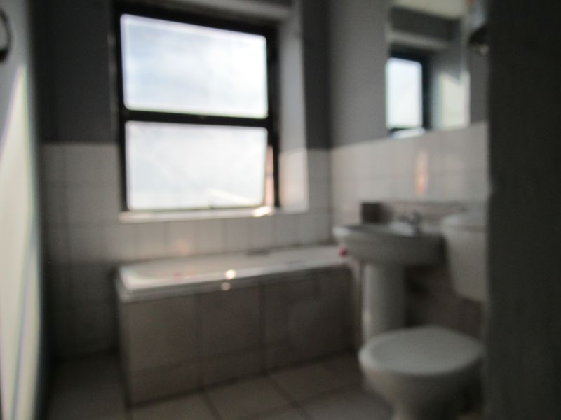 A functional bathroom featuring a bathtub, pedestal basin, and toilet with tiled finishes, requiring a clear, high-quality image for accurate assessment.