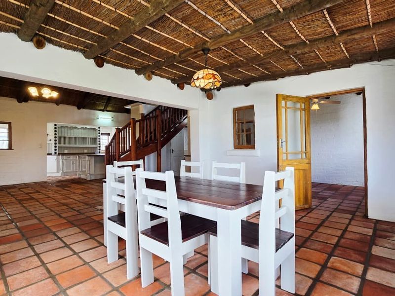 Spacious open-plan living and dining area featuring a traditional thatched ceiling with exposed timber beams and classic terracotta floor tiles.