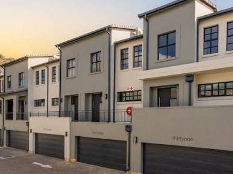 Modern multi-level townhouse complex featuring contemporary architectural design, paved driveway access, and integrated automated garages.