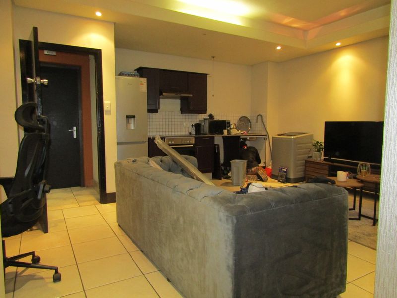 Open-plan living area featuring a kitchen with dark cabinetry and tiled flooring, requiring minor repairs to cabinetry and finishes.