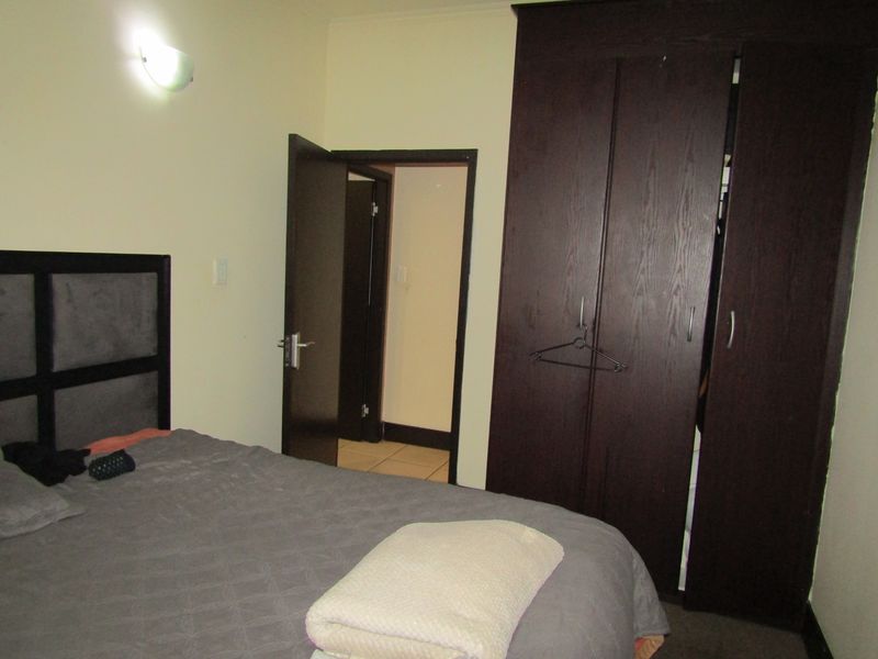 A bedroom featuring a dark wood built-in wardrobe and a wall-mounted light fixture, providing functional storage and lighting.