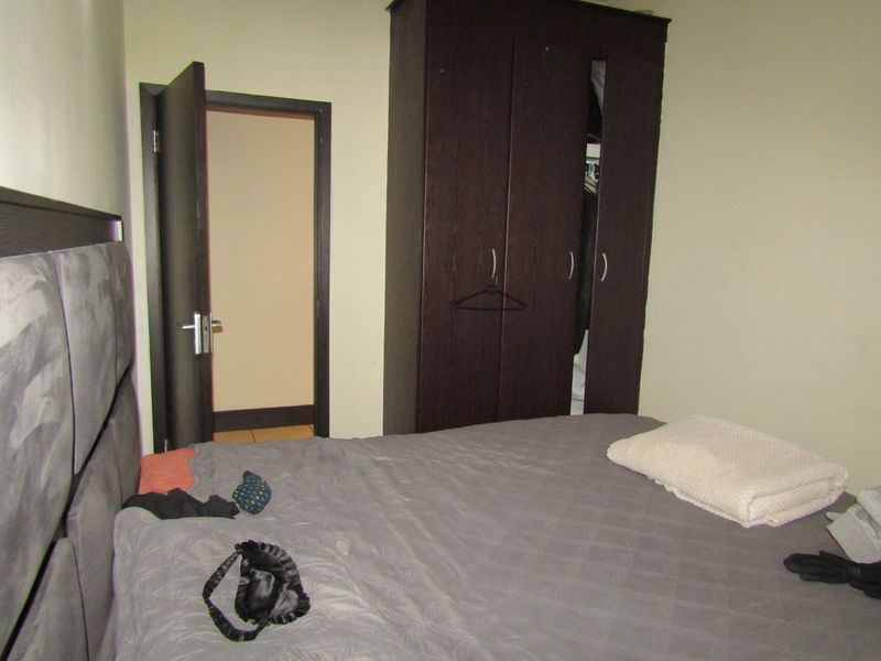 A bedroom featuring a dark wood built-in wardrobe and an internal door leading to an adjacent space.