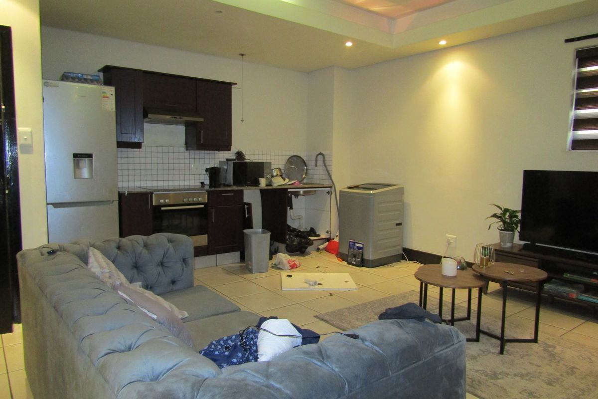 Open-plan living area featuring a compact kitchen with dark cabinetry, tiled flooring, and recessed lighting, requiring minor repairs to cabinetry and finishes.