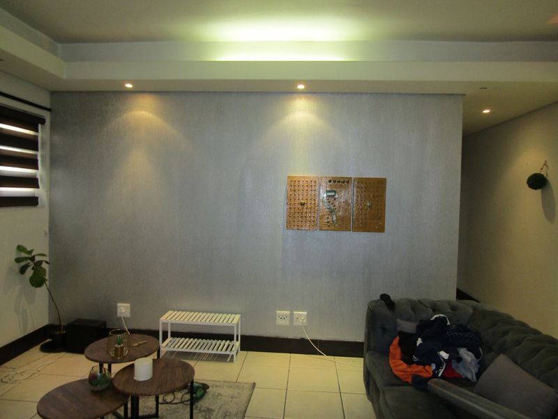 A living room featuring tiled flooring, recessed ceiling lighting with cove accents, and neutral wall finishes.