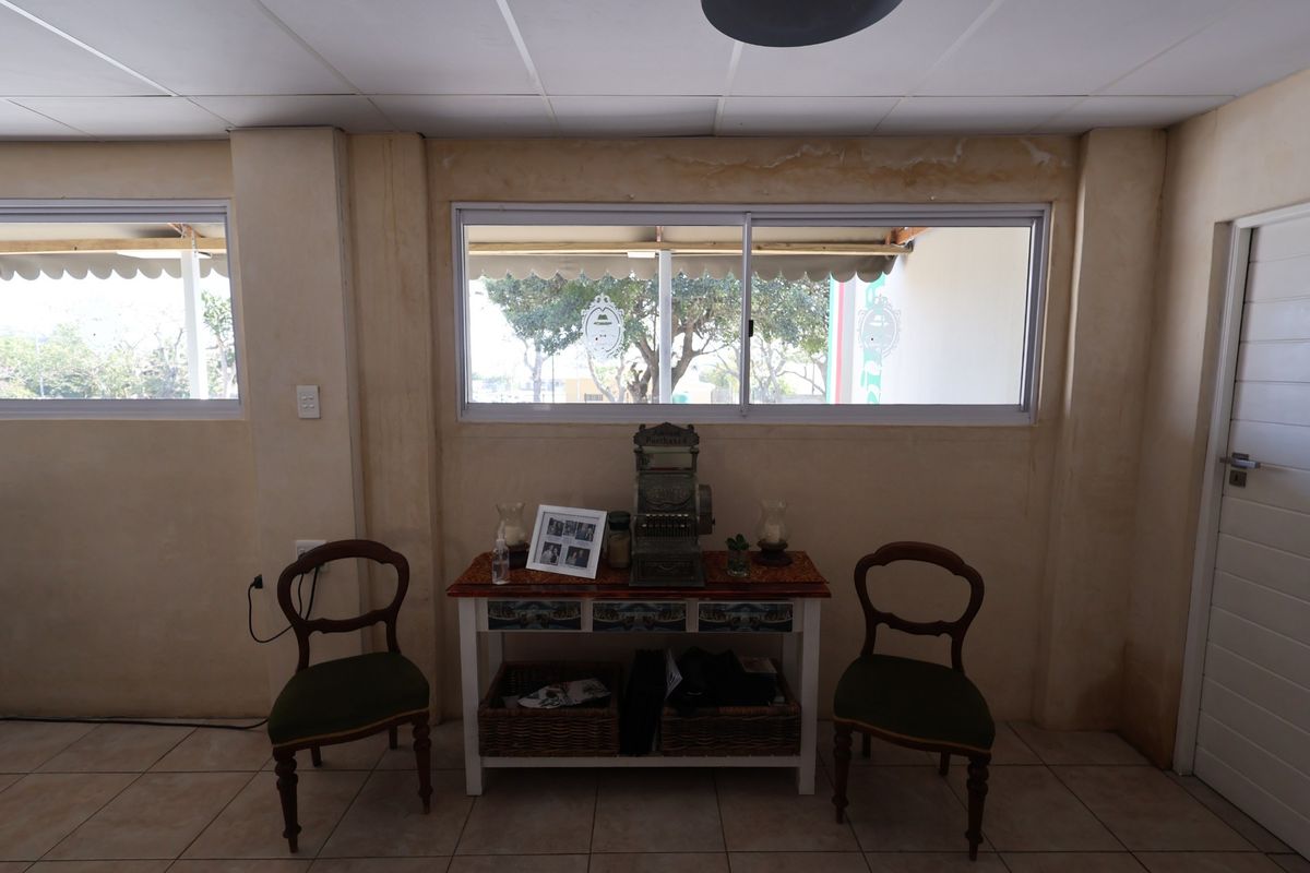 Interior view of a restaurant space featuring tiled flooring, sliding windows, and a suspended ceiling, showing signs of wall water damage.