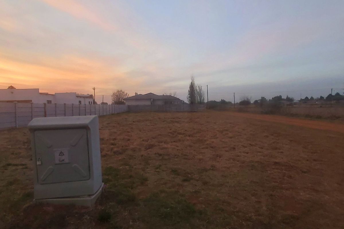 A vacant residential plot featuring a precast concrete boundary wall and an installed electrical utility box at sunset.