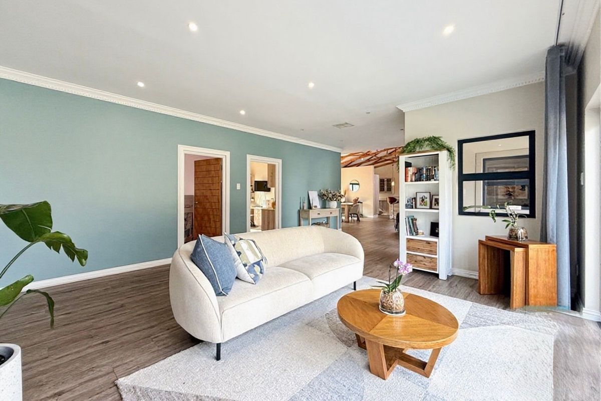 A bright and spacious living room featuring modern laminate flooring, recessed downlighting, and elegant crown molding, creating a welcoming and well-maintained living space.