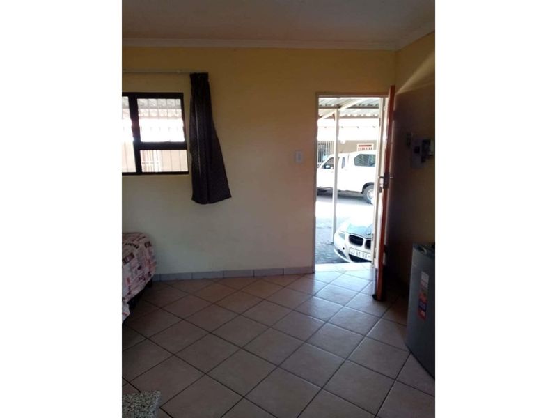 A living area featuring tiled flooring and direct access to the exterior driveway.