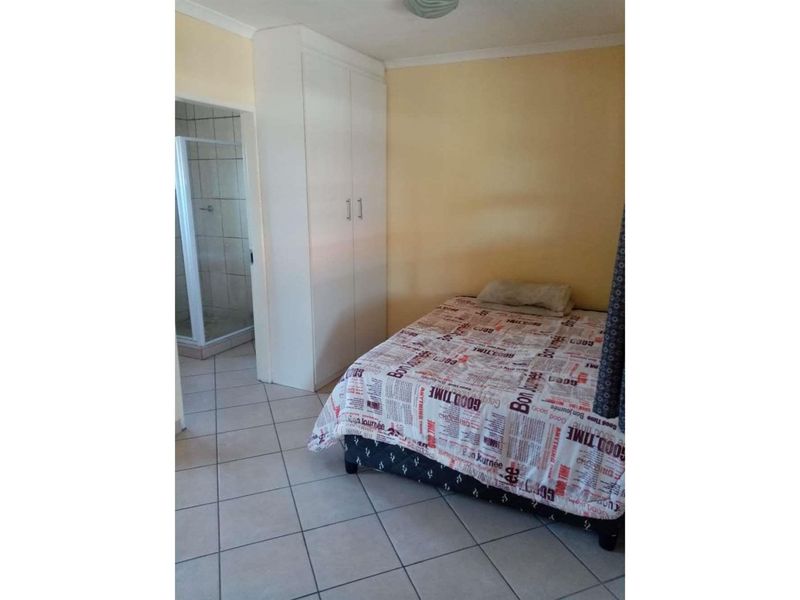 A functional bedroom featuring tiled flooring, a built-in wardrobe, and direct access to an en-suite bathroom.