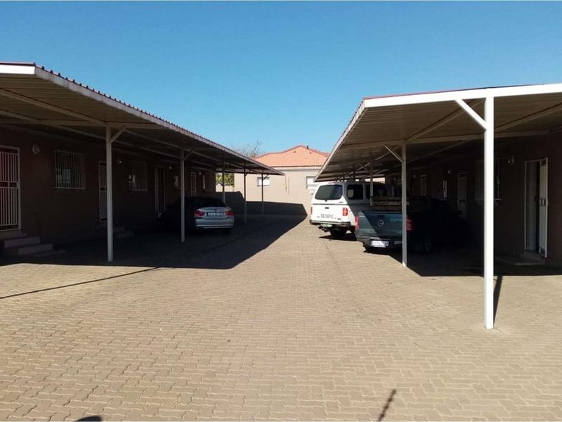 A paved driveway area featuring covered carports providing sheltered parking for multiple vehicles.