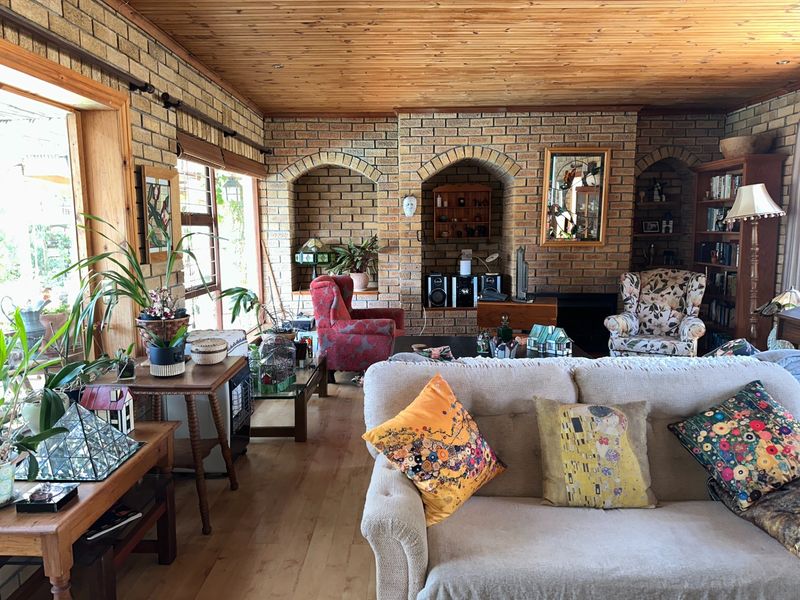 Spacious living room featuring exposed brick walls, timber ceiling, and built-in brick arched alcoves with a fireplace.