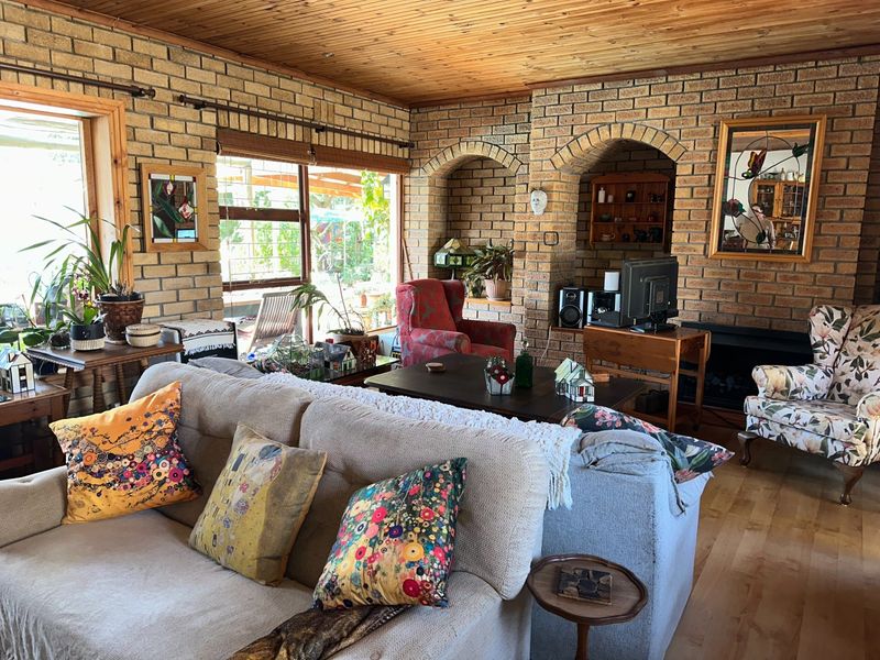 A cozy living room featuring exposed brick walls, a timber ceiling, and built-in arched alcoves surrounding a fireplace, creating a rustic and character-filled space.