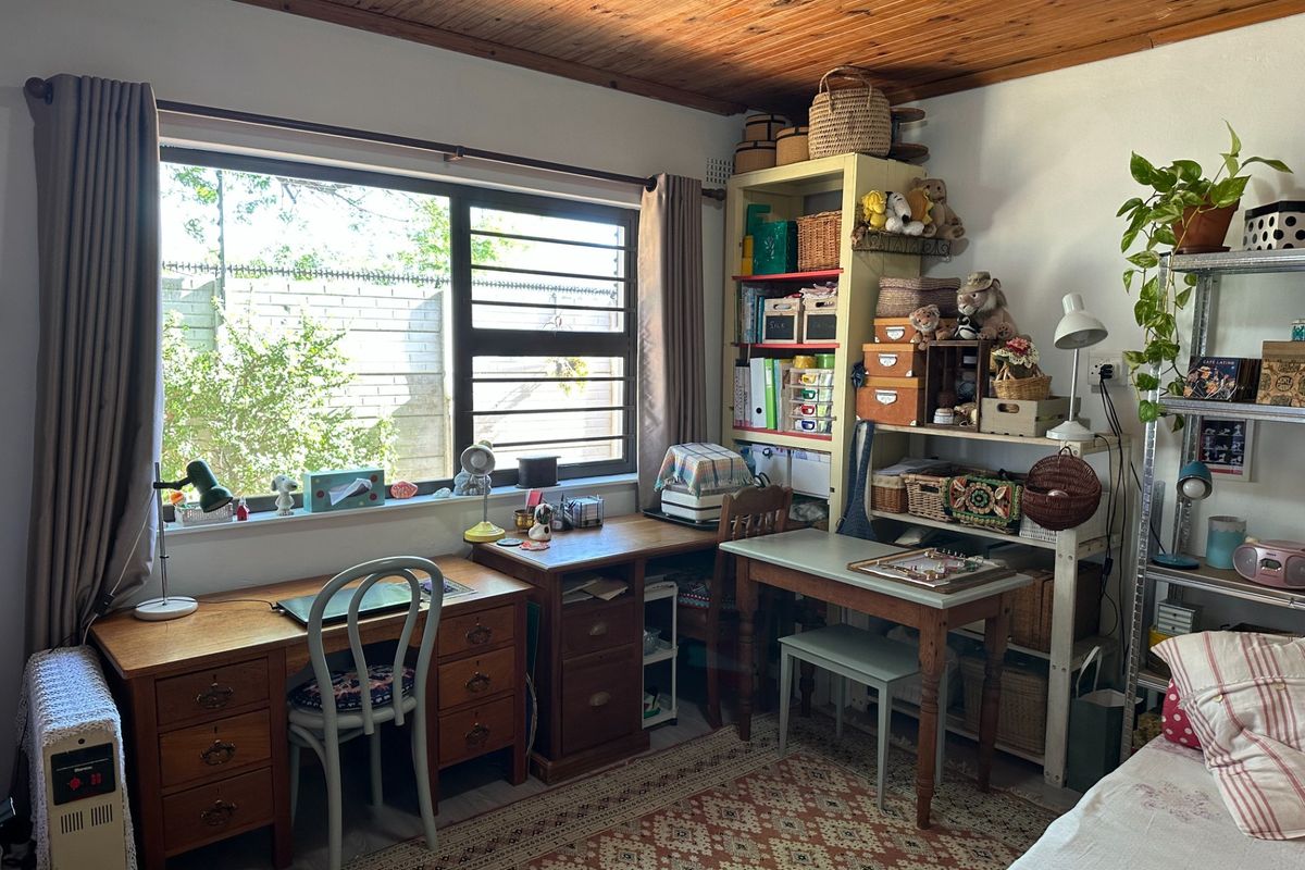 A bedroom featuring a timber-clad ceiling and a large window with security bars, providing natural light and a view of the exterior.