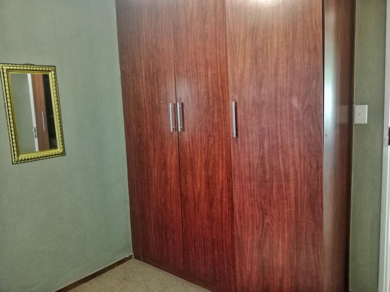 A bedroom featuring a large built-in wooden wardrobe and carpeted flooring.