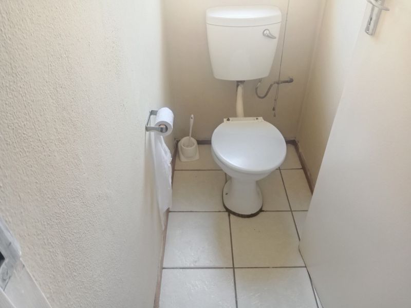 A compact, functional guest toilet featuring ceramic floor tiles and standard sanitary ware, requiring minor cosmetic updates.