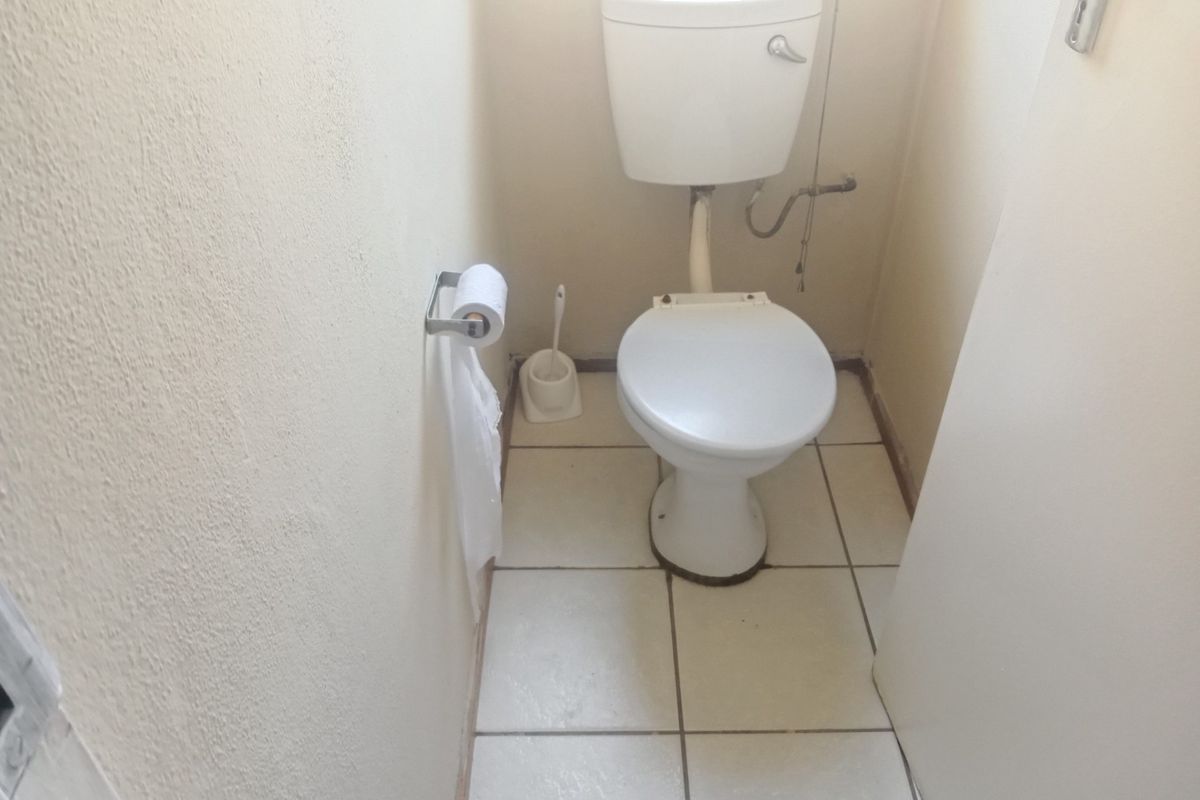 A compact, functional guest toilet featuring ceramic floor tiles and standard sanitary ware, requiring minor cosmetic updates.