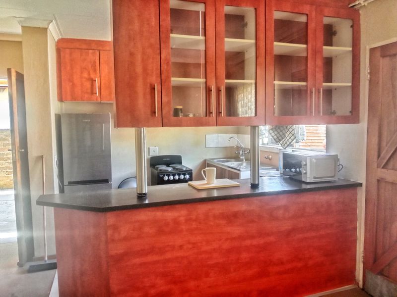 A functional kitchen featuring wooden cabinetry, a breakfast bar, a built-in stove, and a stainless steel sink with a tiled backsplash.