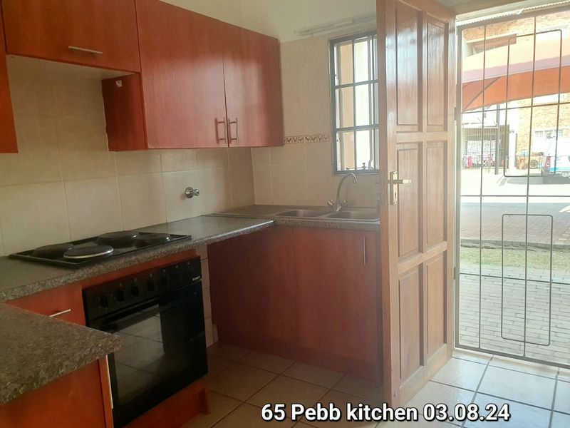 A functional kitchen featuring built-in cabinetry, laminate countertops, a stainless steel sink, and an integrated oven with an electric hob.