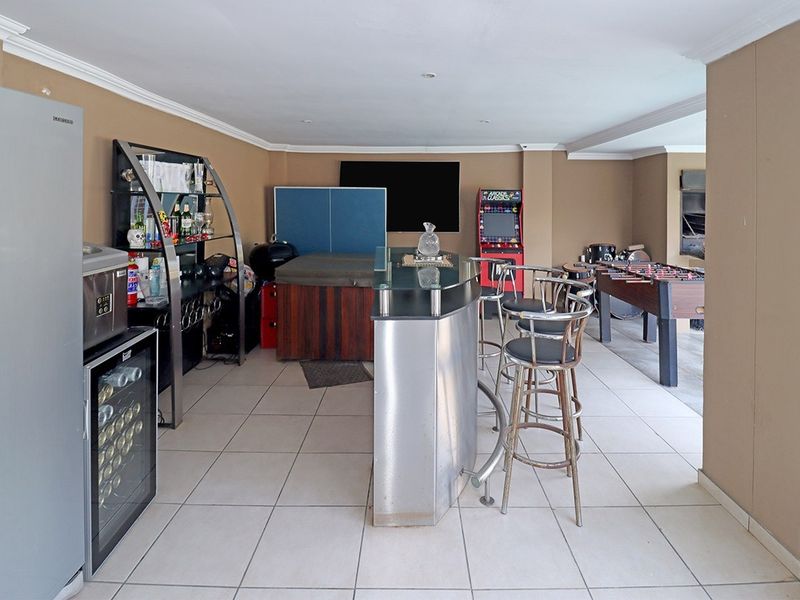 Spacious entertainment area featuring a built-in bar counter and tiled flooring, suitable for a home pub or games room setup.