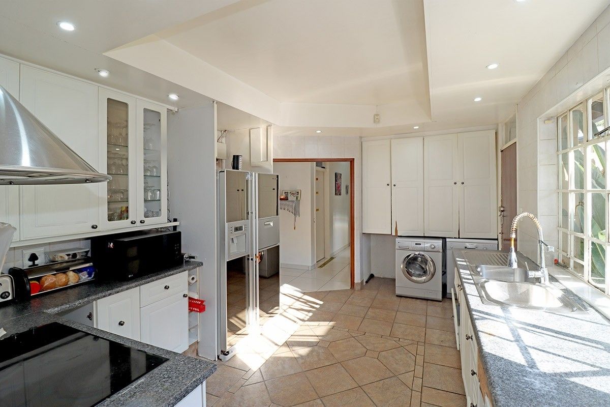 Spacious kitchen featuring white cabinetry, granite countertops, integrated laundry appliances, and tiled flooring with ample natural light.
