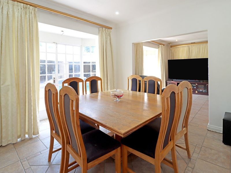 Open-plan dining and living area featuring tiled flooring, recessed lighting, and direct access to the outdoor space through french doors.