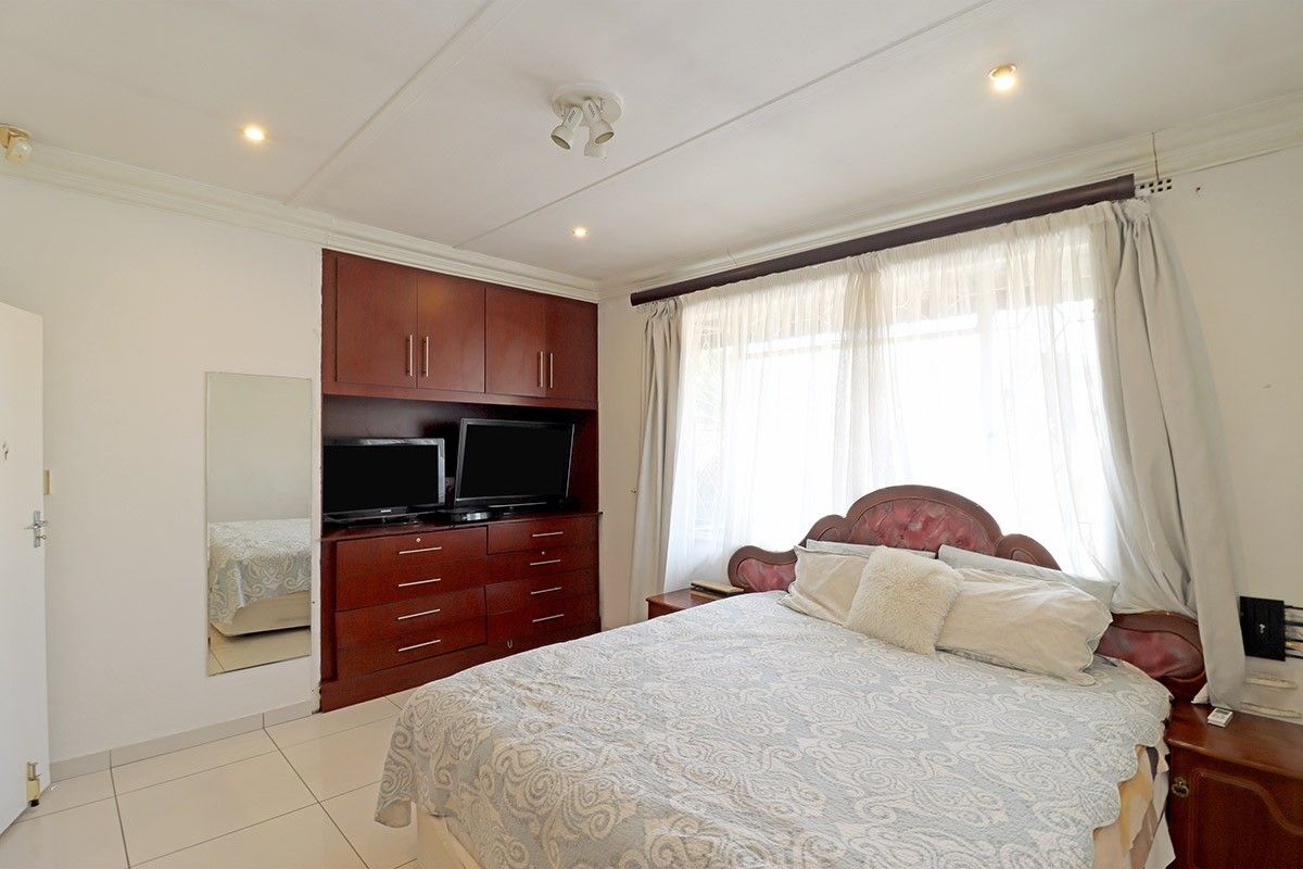 A bedroom featuring built-in wooden cabinetry, tiled flooring, and recessed ceiling lighting, offering a functional and well-maintained living space.