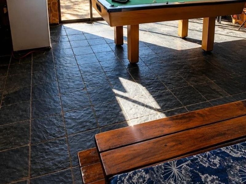 Spacious entertainment area featuring rustic stone wall cladding, durable slate floor tiles, and large sliding glass doors providing access to the outdoor space.