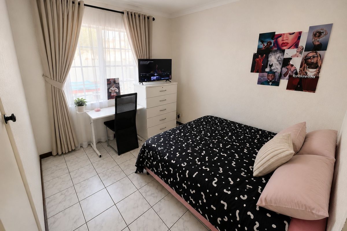A functional bedroom featuring tiled flooring and a window with curtain rails, providing a neutral base for personalization.