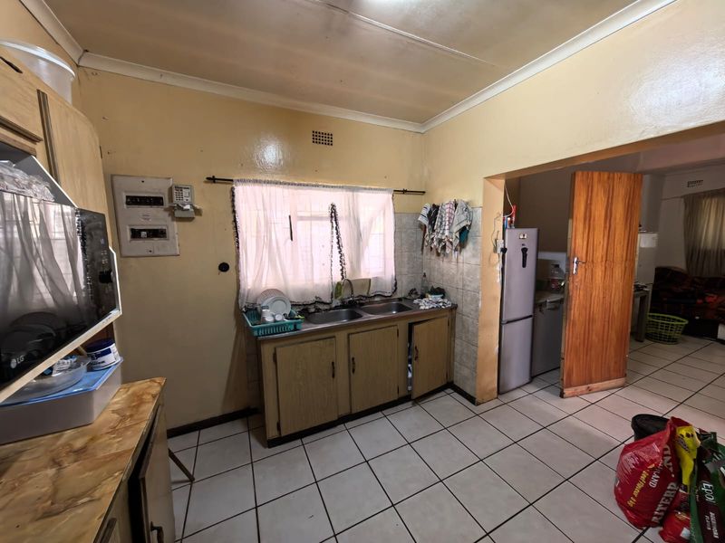 A functional kitchen featuring tiled flooring, laminate cabinetry, and a double sink, offering potential for modernization and cosmetic updates.