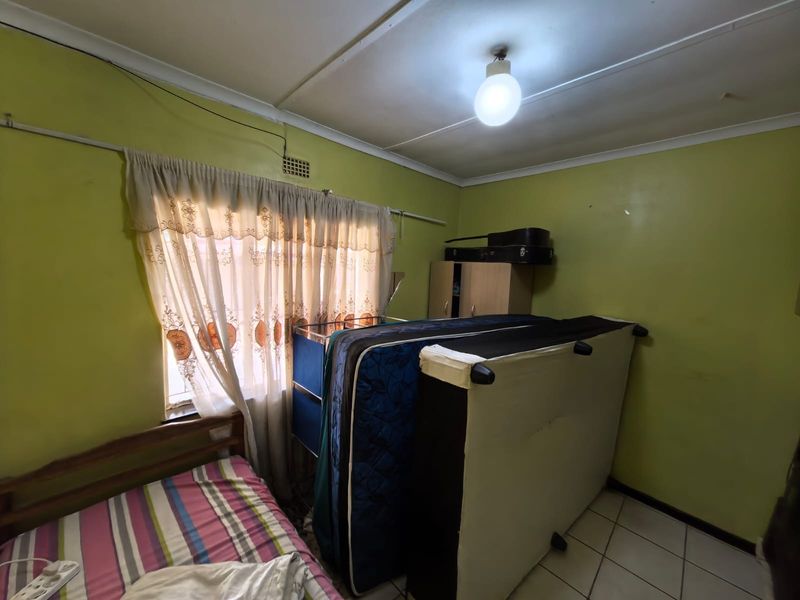 A bedroom featuring tiled flooring and a ceiling vent, currently used for storage. The space requires cosmetic updates to improve its overall appeal.
