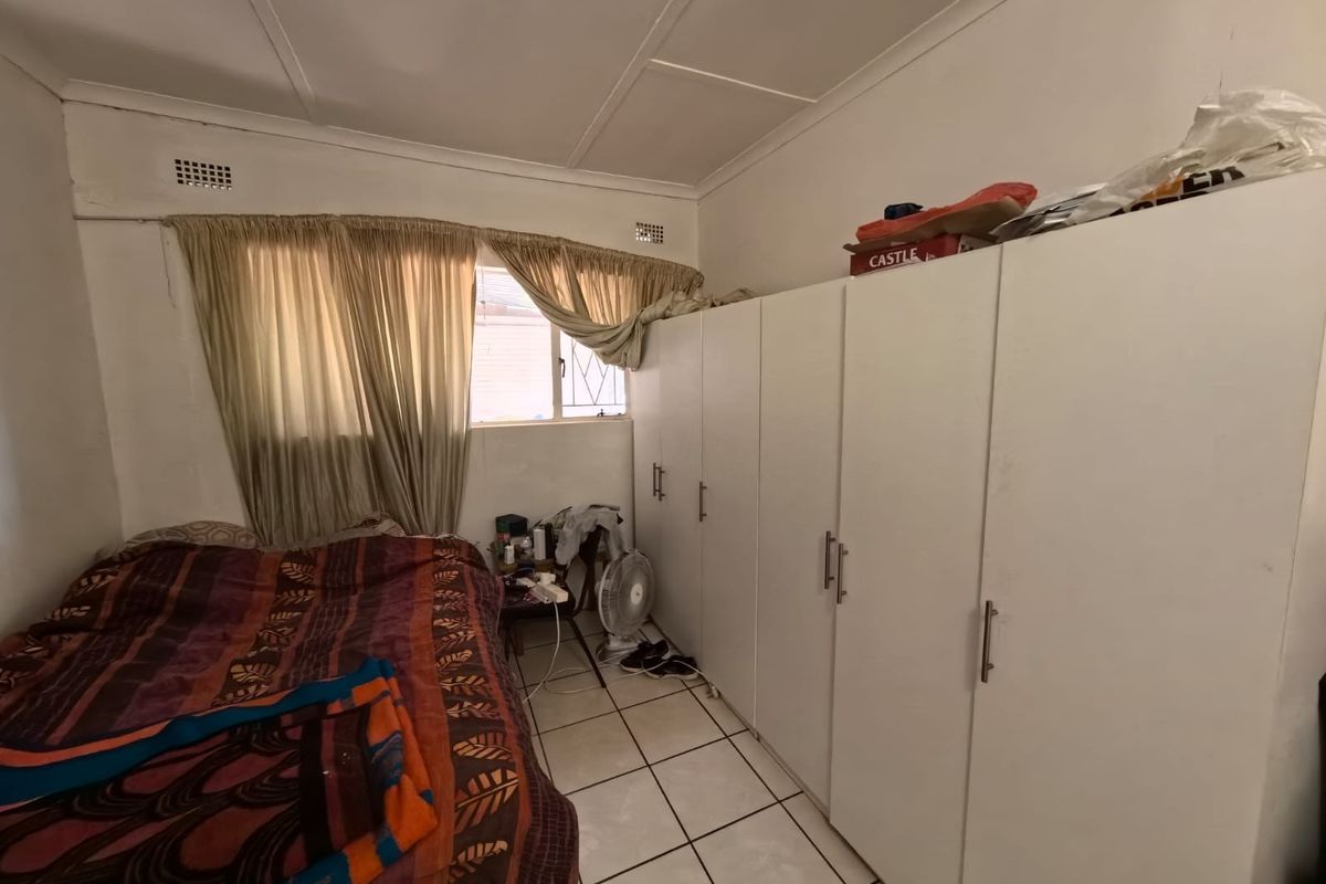 A bedroom featuring built-in cupboards and tiled flooring, requiring cosmetic updates to improve the overall condition and appeal.