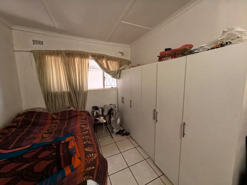 A bedroom featuring built-in cupboards and tiled flooring, requiring cosmetic updates to improve the overall condition and appeal.