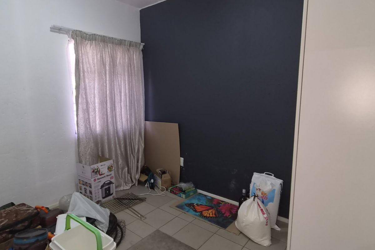 A small bedroom featuring tiled flooring and a built-in cupboard, currently used for storage.