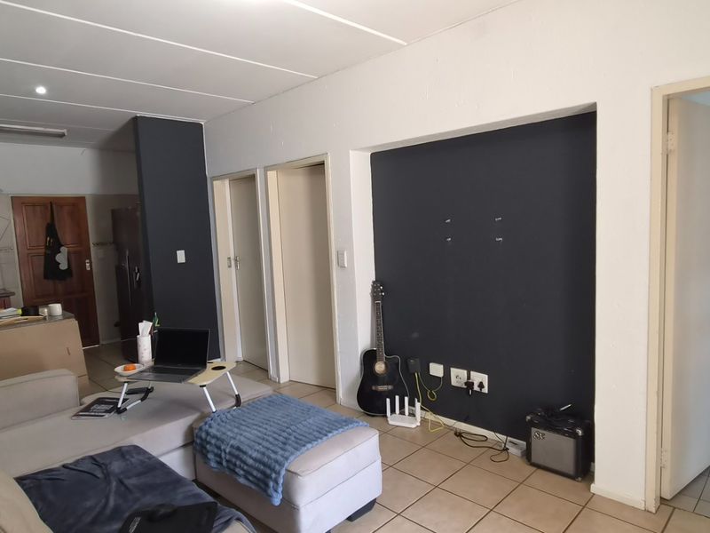 Open-plan living area featuring tiled flooring, recessed lighting, and an integrated kitchen space, with direct access to adjacent rooms.