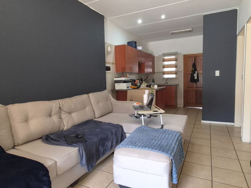 Open plan living area featuring tiled flooring and a functional kitchen with built-in cabinetry, creating a versatile space for daily living.