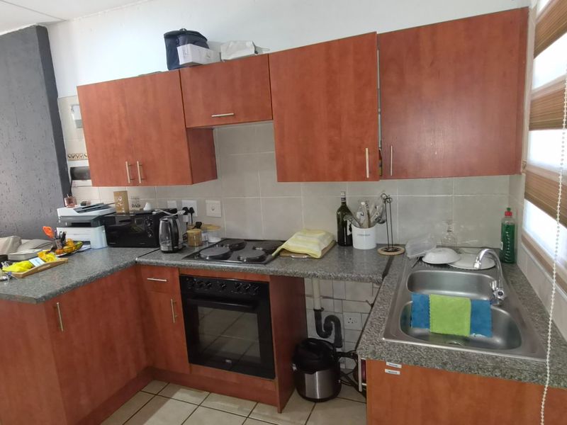 Open-plan kitchen featuring laminate cabinetry, granite countertops, built-in oven, electric hob, and a double bowl stainless steel sink with tiled backsplash.