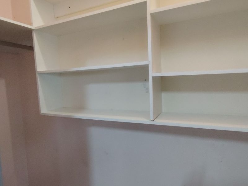 A utility storage area featuring built-in white shelving units, suitable for office supplies or general storage organization.
