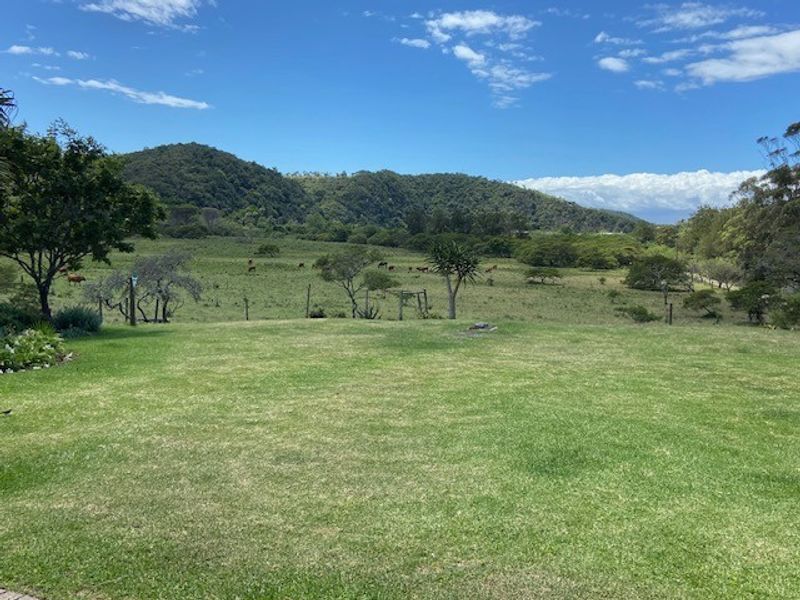 A scenic view of a lush green lawn overlooking a rural landscape with rolling hills and open fields.