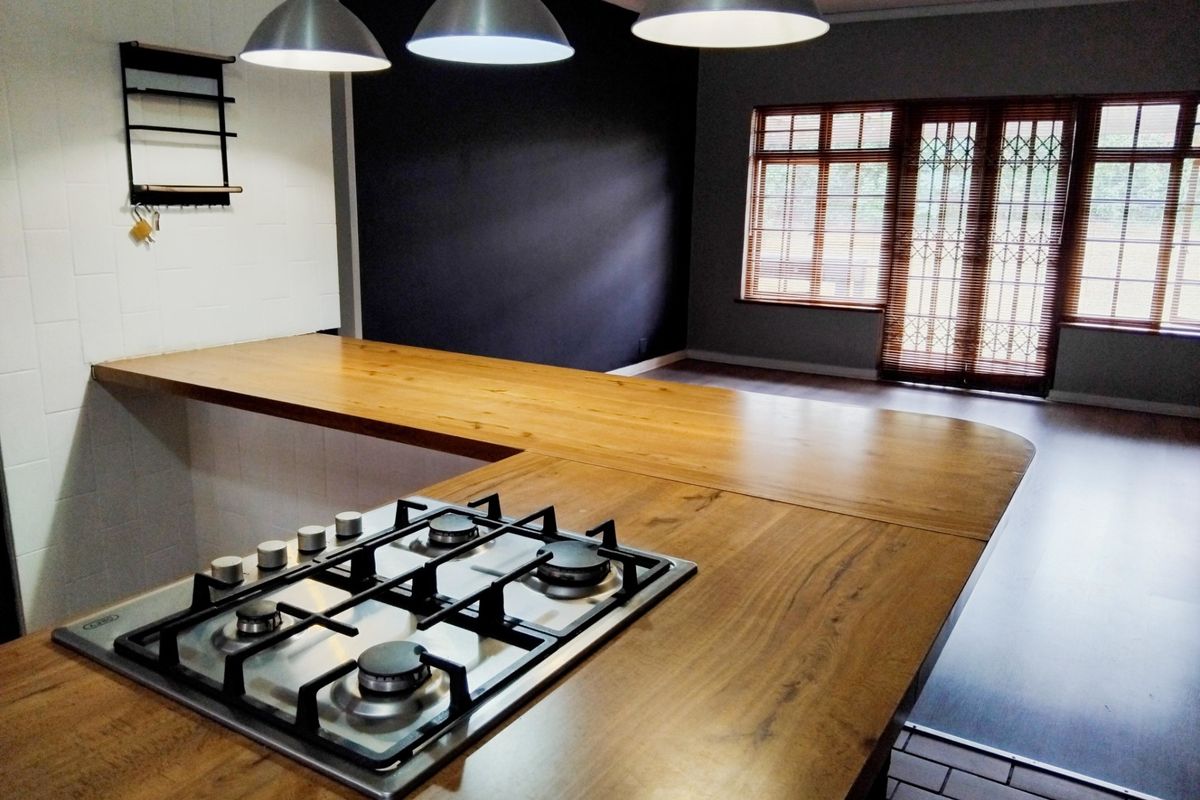 Modern kitchen featuring a wooden breakfast bar with an integrated gas cooktop, pendant lighting, and direct access to the outdoor area.