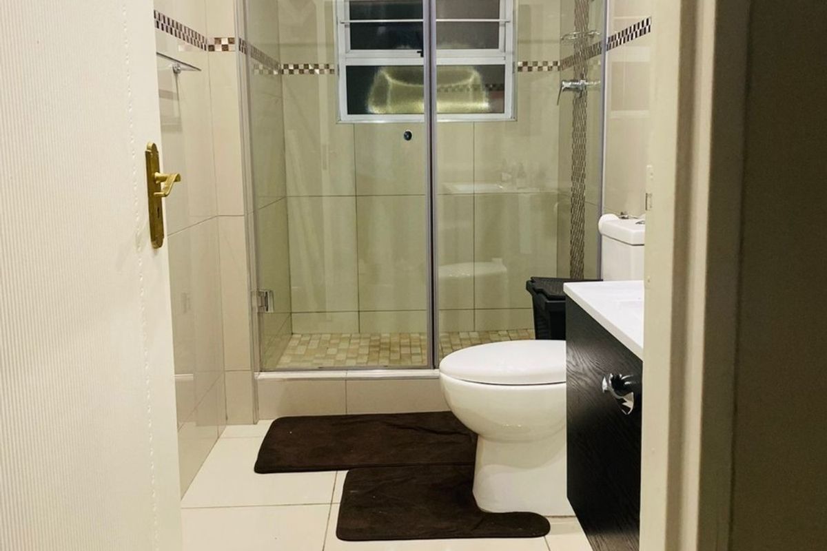 A modern, well-maintained bathroom featuring a glass-enclosed shower, built-in vanity, and neutral tiled finishes throughout.