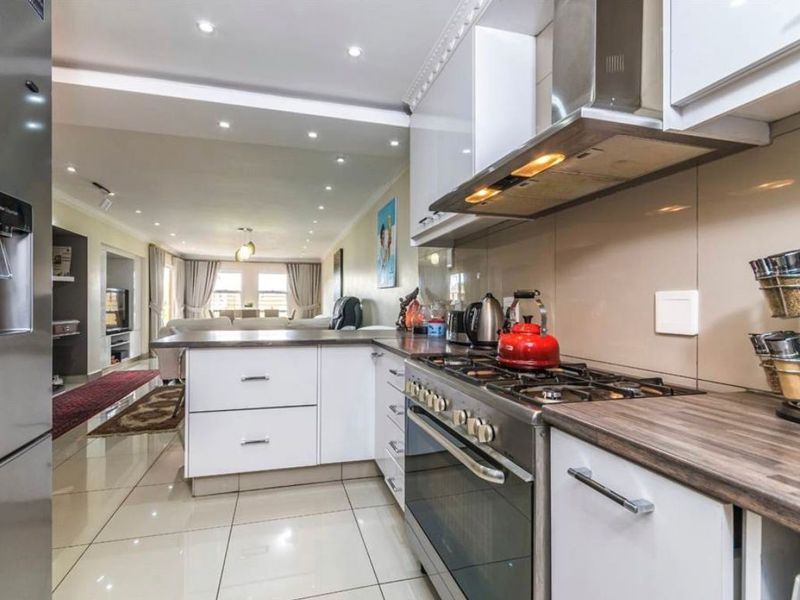 Modern open-plan kitchen featuring white cabinetry, laminate countertops, and a gas stove, seamlessly flowing into the adjacent living and dining area.