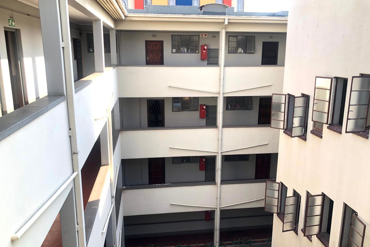 View of the apartment complex central courtyard featuring multi-level balcony walkways, security gates, and fire safety equipment.