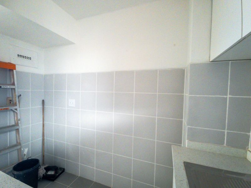 A functional kitchen area featuring neutral wall tiles, built-in cabinetry, and a clean countertop surface, ready for personalization.